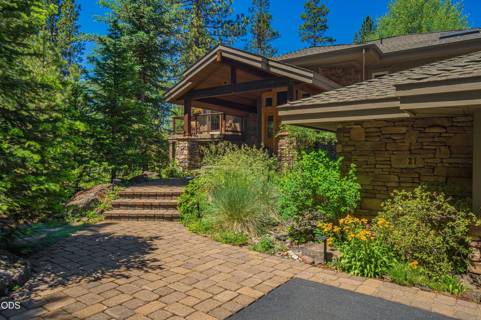 A gently rising paver walkway winds through native rock, mature trees and thoughtfully planted landscaping toward the covered entry, creating an arrival that feels private, established and distinctly Sunriver.