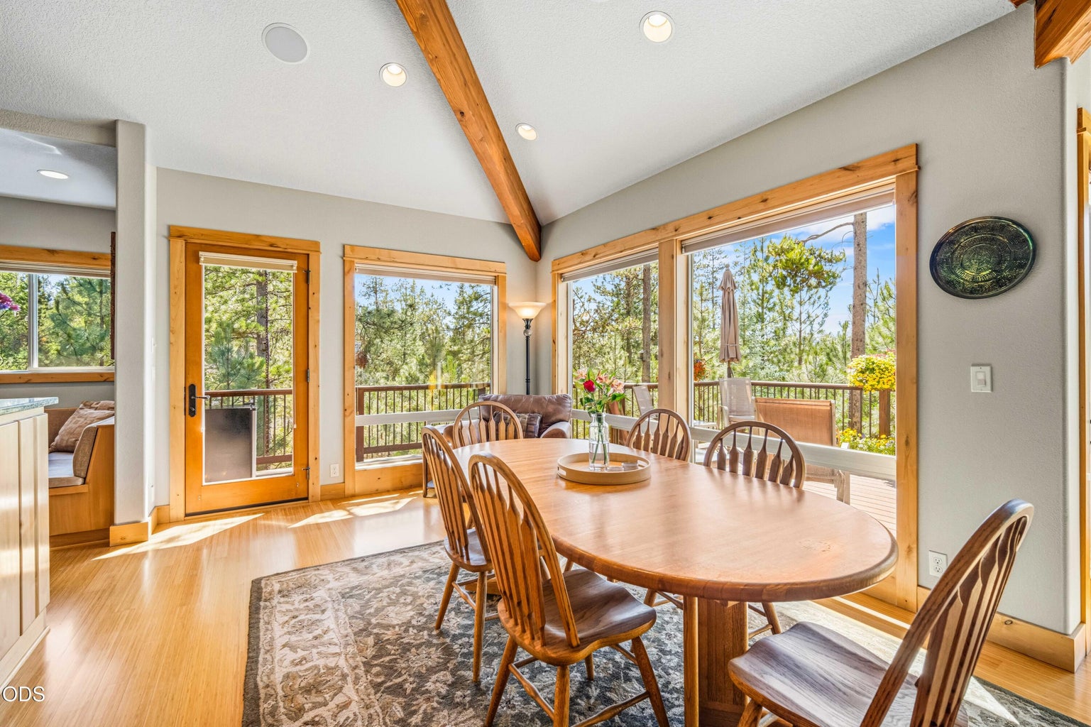 The dining area flows naturally into the great room while retaining its own sense of place, surrounded by windows, exposed beams and views across the upper deck toward the forest and Mt. Bachelor.