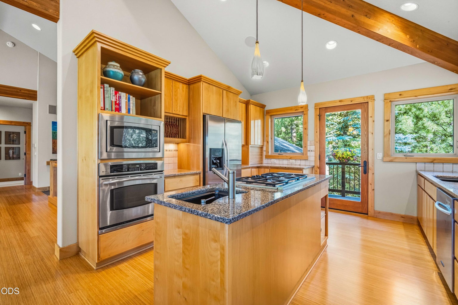 The spacious kitchen features extensive natural wood cabinetry, granite surfaces, stainless appliances, vaulted ceilings and a central island with gas cooktop and preparation sink.