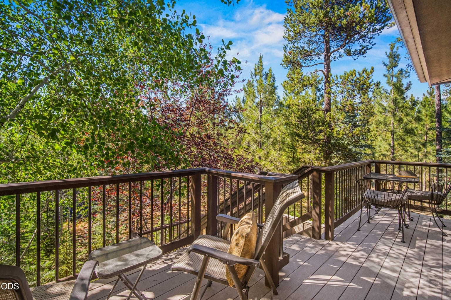 An elevated rear view reveals the impressive system of decks, patios and exterior stairs wrapping the home and connecting the primary suite, dining area, great room and lower outdoor spaces.