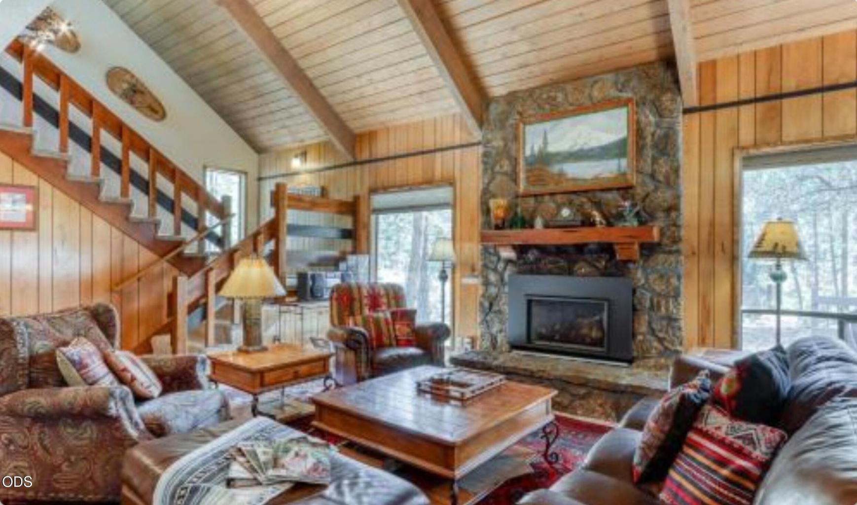 Classic Sunriver living room with vaulted wood ceilings, exposed beams, and a floor-to-ceiling lava rock fireplace as the central gathering space.