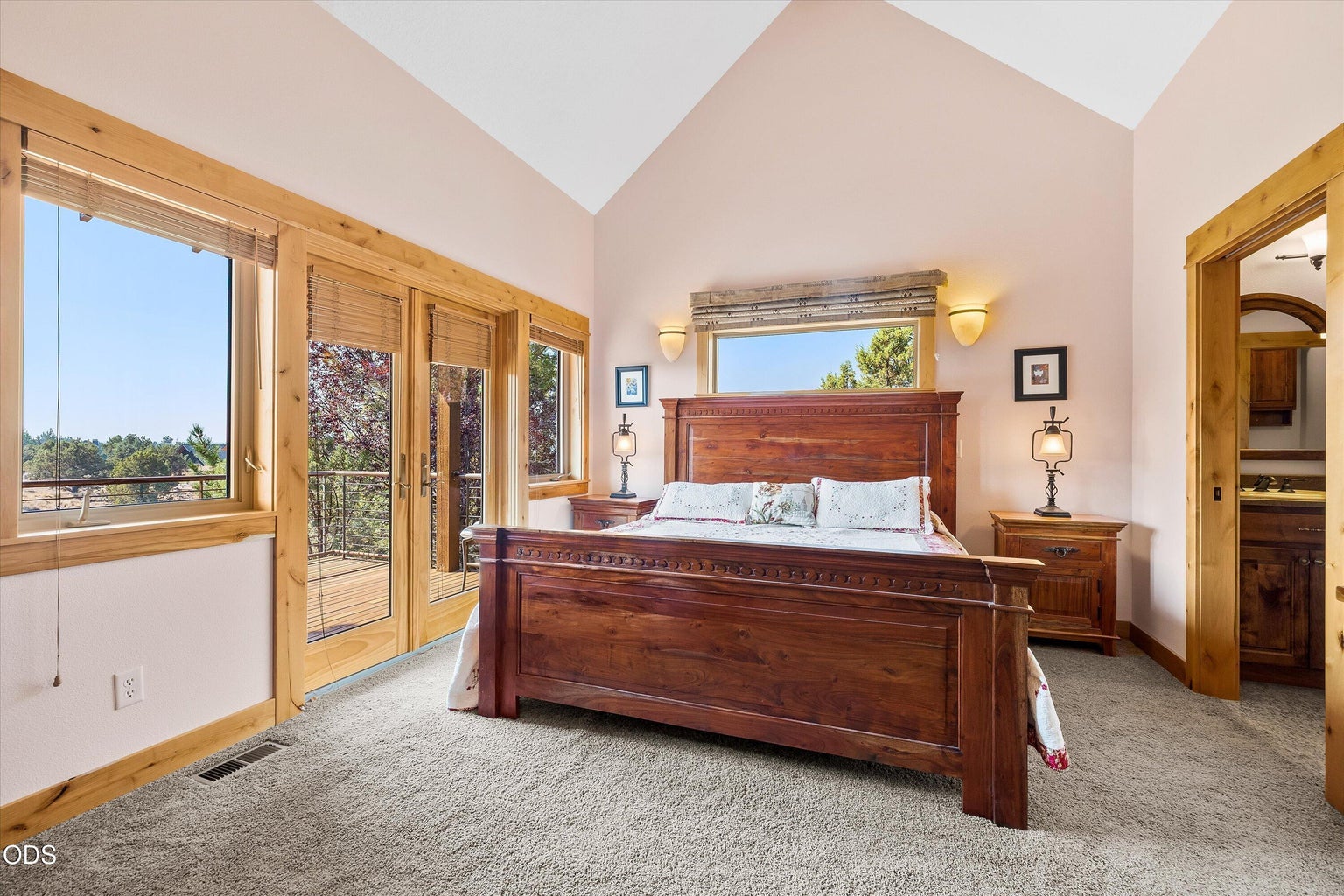Primary bedroom one leads to deck and hot tub, features vaulted ceilings and luxurious spa-like ensuite