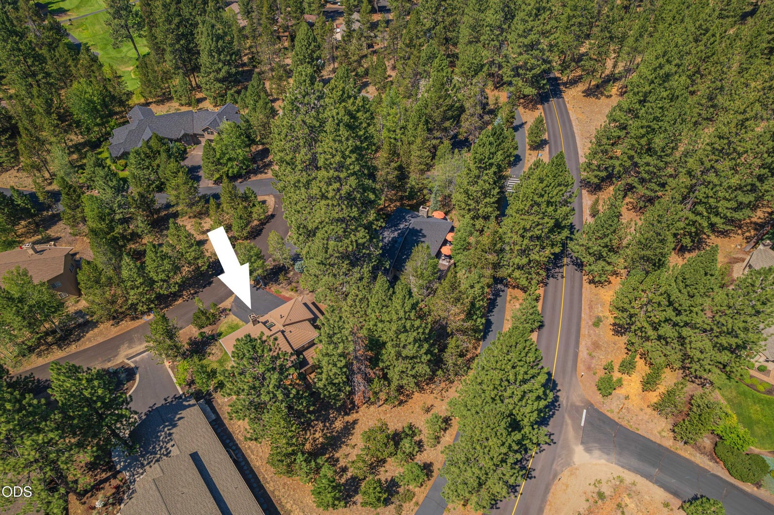 An aerial view highlights the home’s wooded Sunriver setting and its position along East Cascade Road, surrounded by the natural beauty and established character of the community.