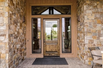 Welcoming covered front entrance with water feature to the left, statement stone and glass finishings